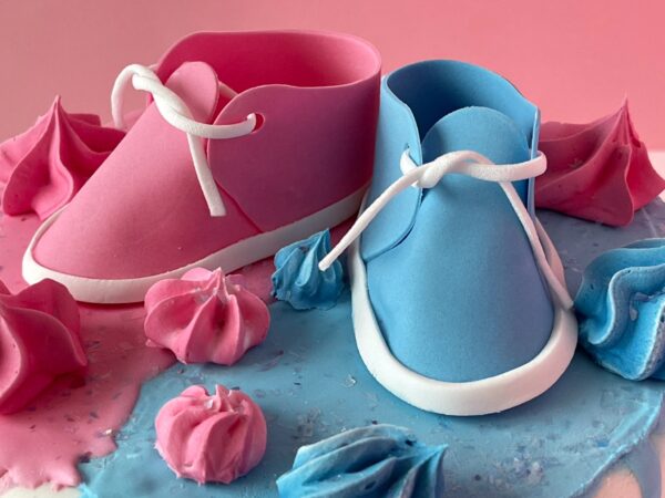 gender reveal cake with baby shoes close